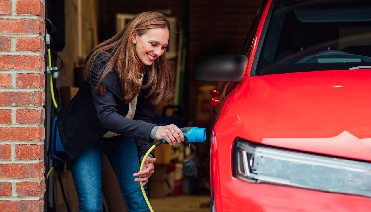 Woman charging her red EV at home