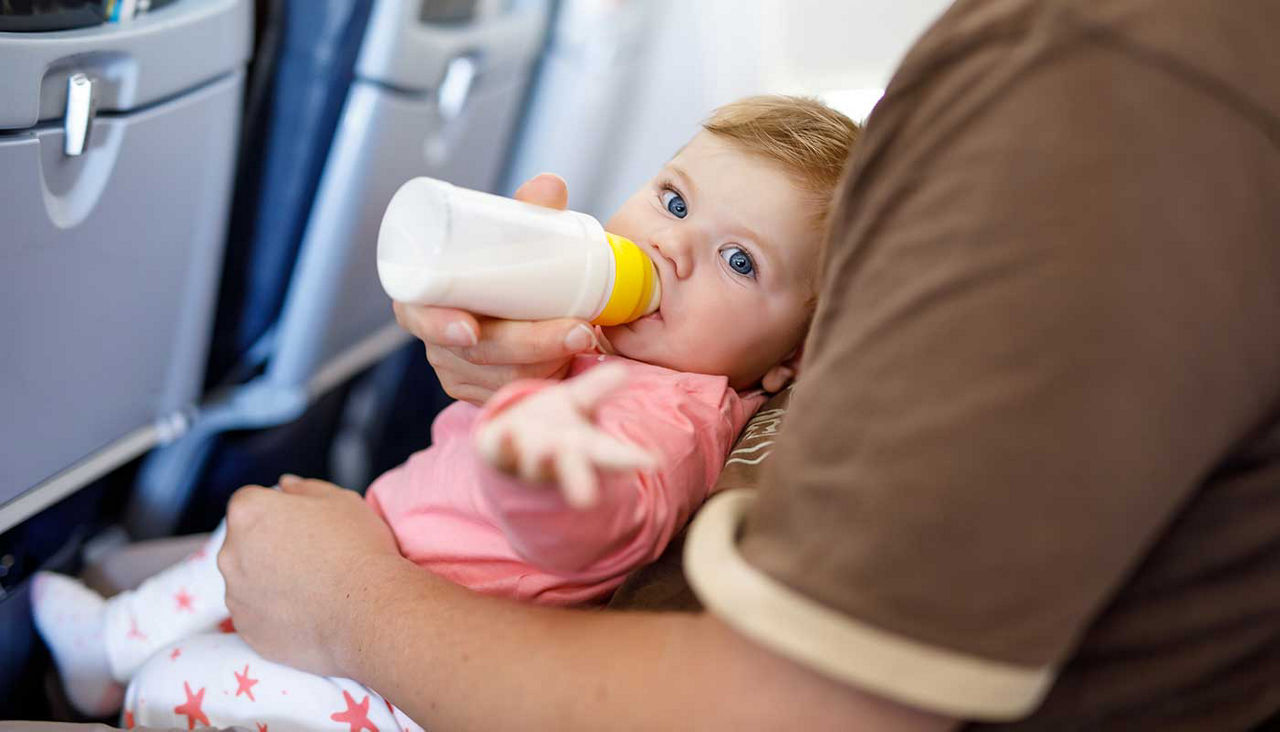 Dad holding his baby daughter during flight on airplane going on vacation