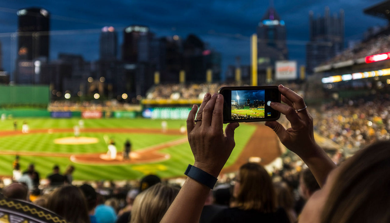 hand holding smartphone or camera filming or photographing baseball game