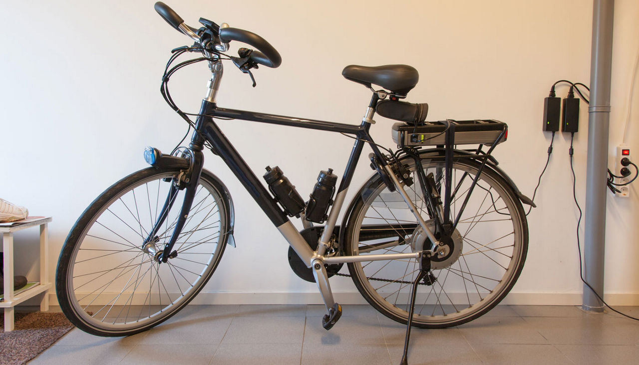 Black electric bicycle in a garage plugged into an outlet