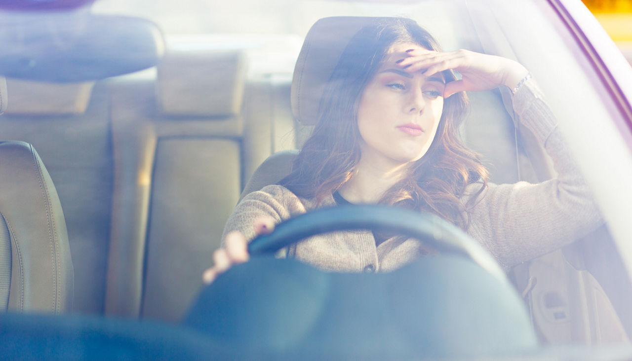 woman sitting in her car while it idles