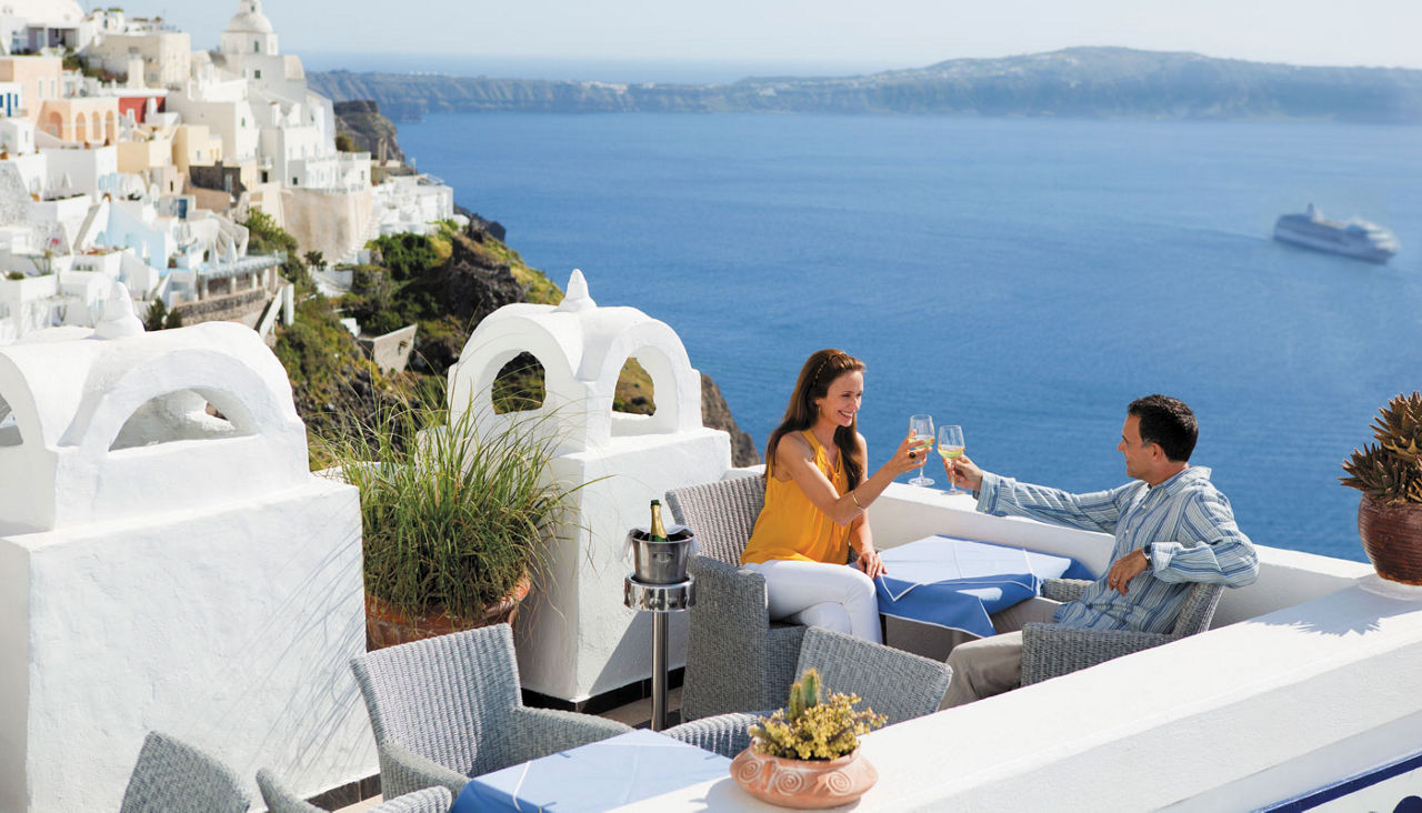 couple drinking champagne with a view off the Santorini coast