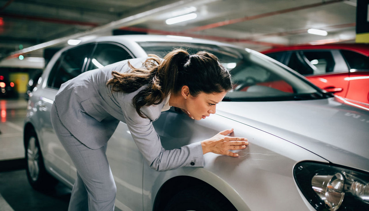 Frustrated woman reviewing scratches on car