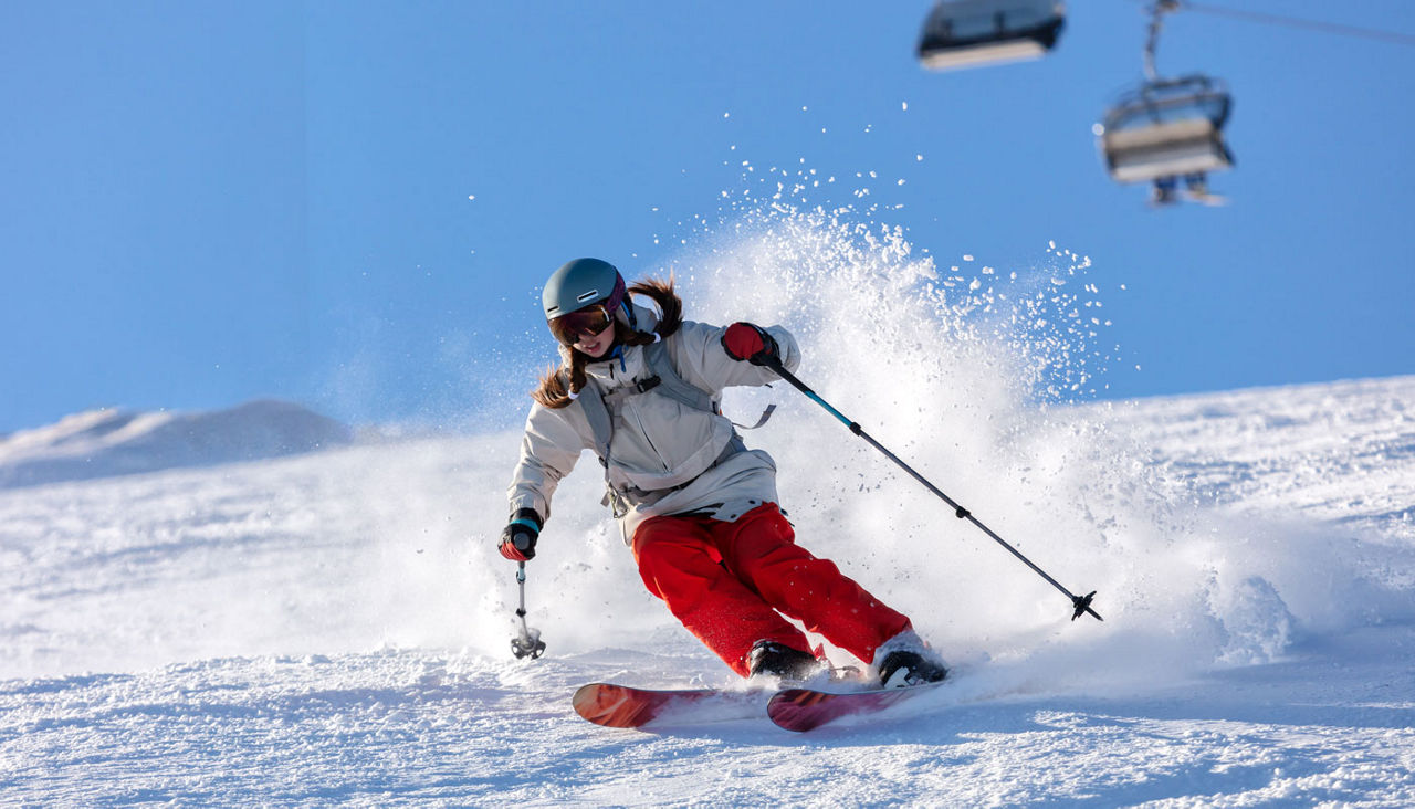 Active winter holidays, woman skiing downhill in sunny day.