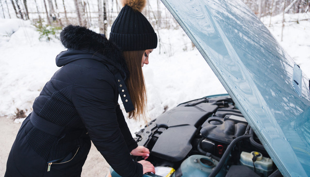 Woman's on the side of the road in snow with her car hood up