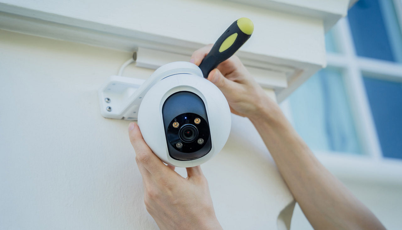 A technician installs a CCTV camera on the facade of a home