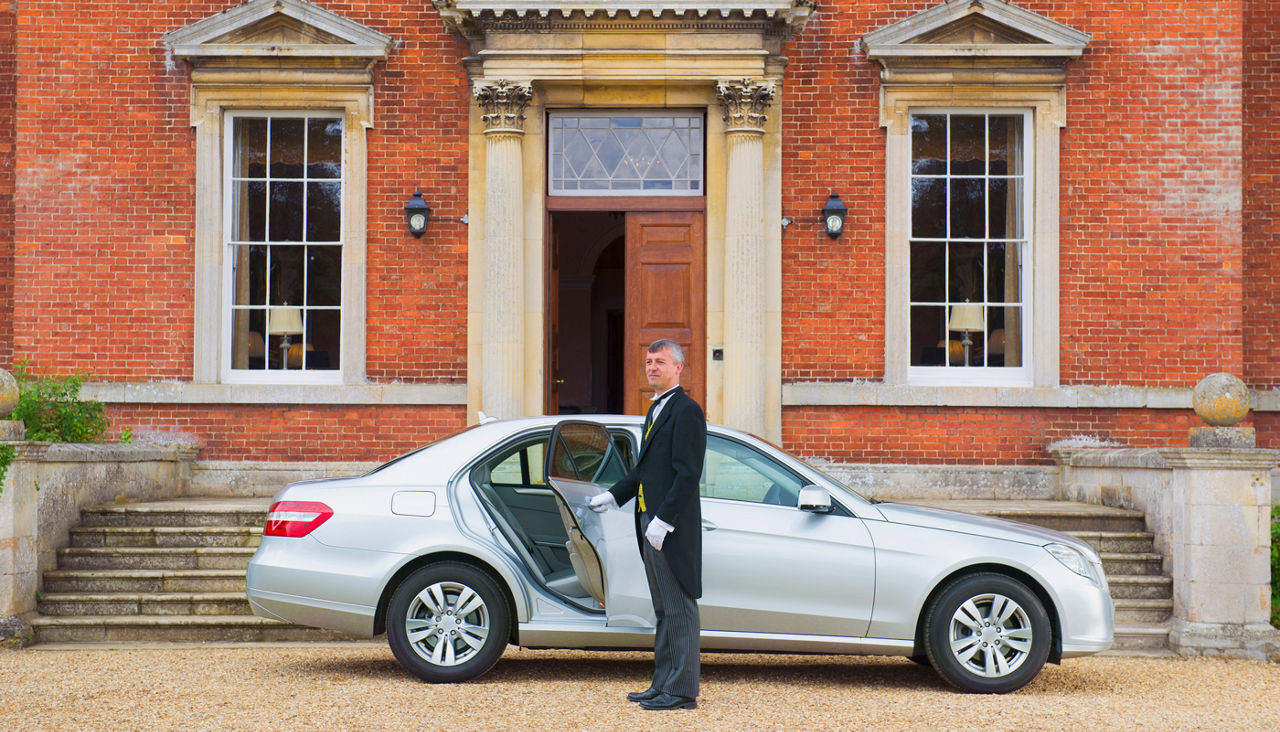 butler opening car door outside mansion