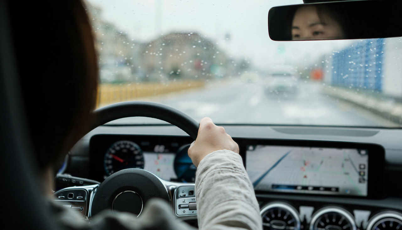 Brunette woman driving a car automobile interior hands on wheel
