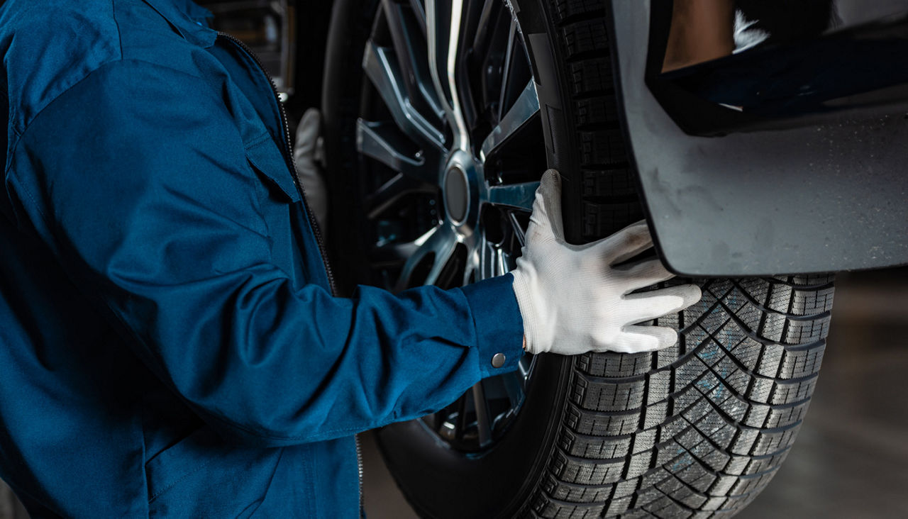 cropped view of mechanic installing new tire on car