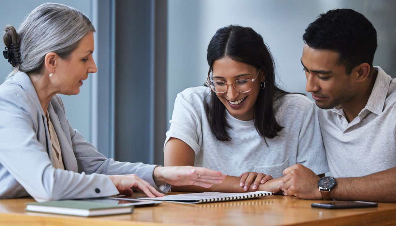Happy young couple reviewing paperwork with a consultant in an office