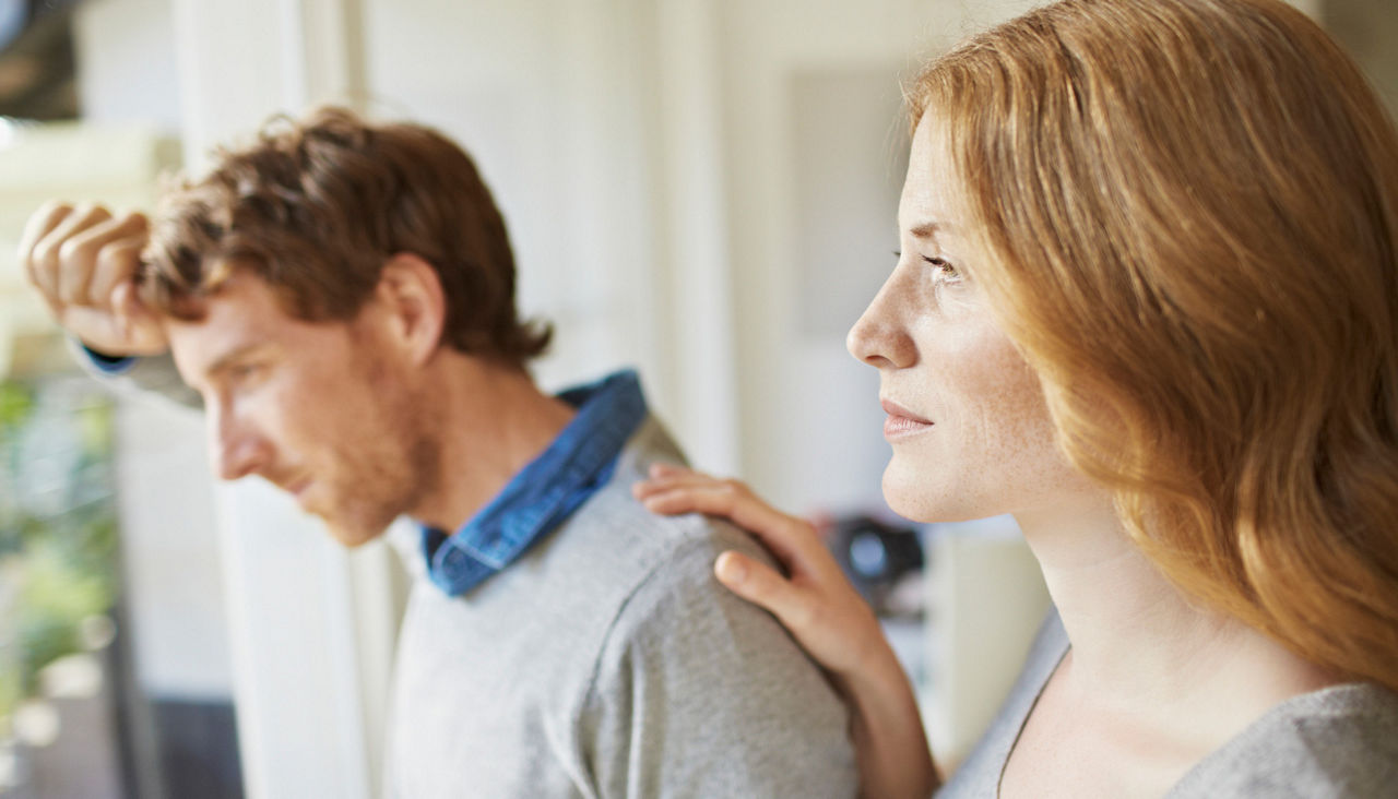 Pensive couple looking out window