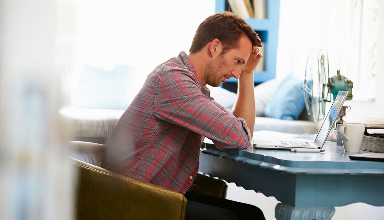 Stressed man at home office desk with laptop