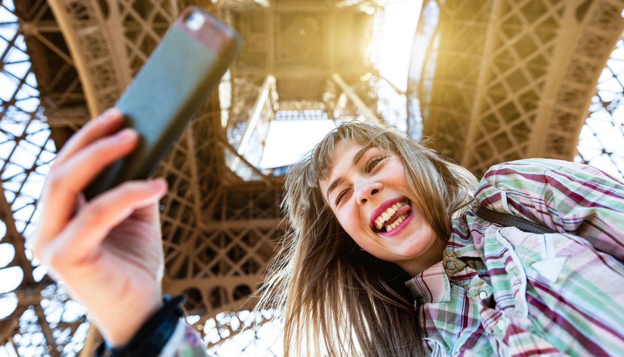 Happy girl taking a selfie under the Eiffel Tower in Paris