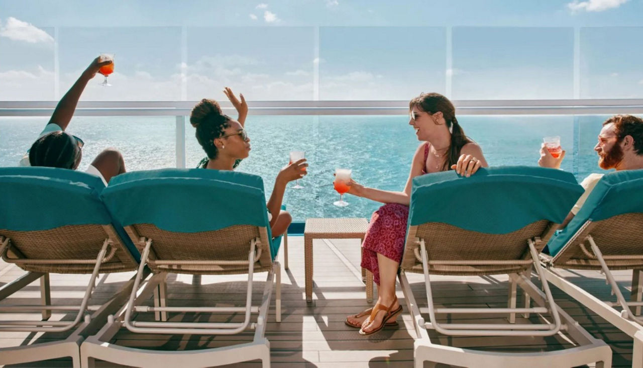 Adults enjoying drinks on cruise deck with overlook of the ocean
