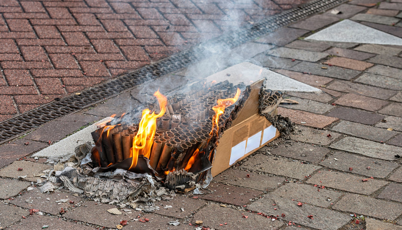 Box of blown out fireworks sitting on brick pavement