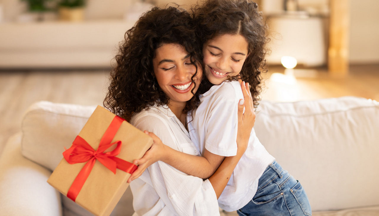 Mother and daughter hugging with a Christmas gift in hand
