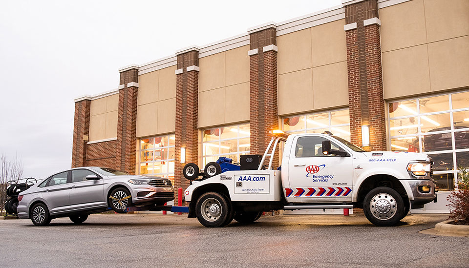 AAA Tow truck with car in tow in front of a Car Care Center