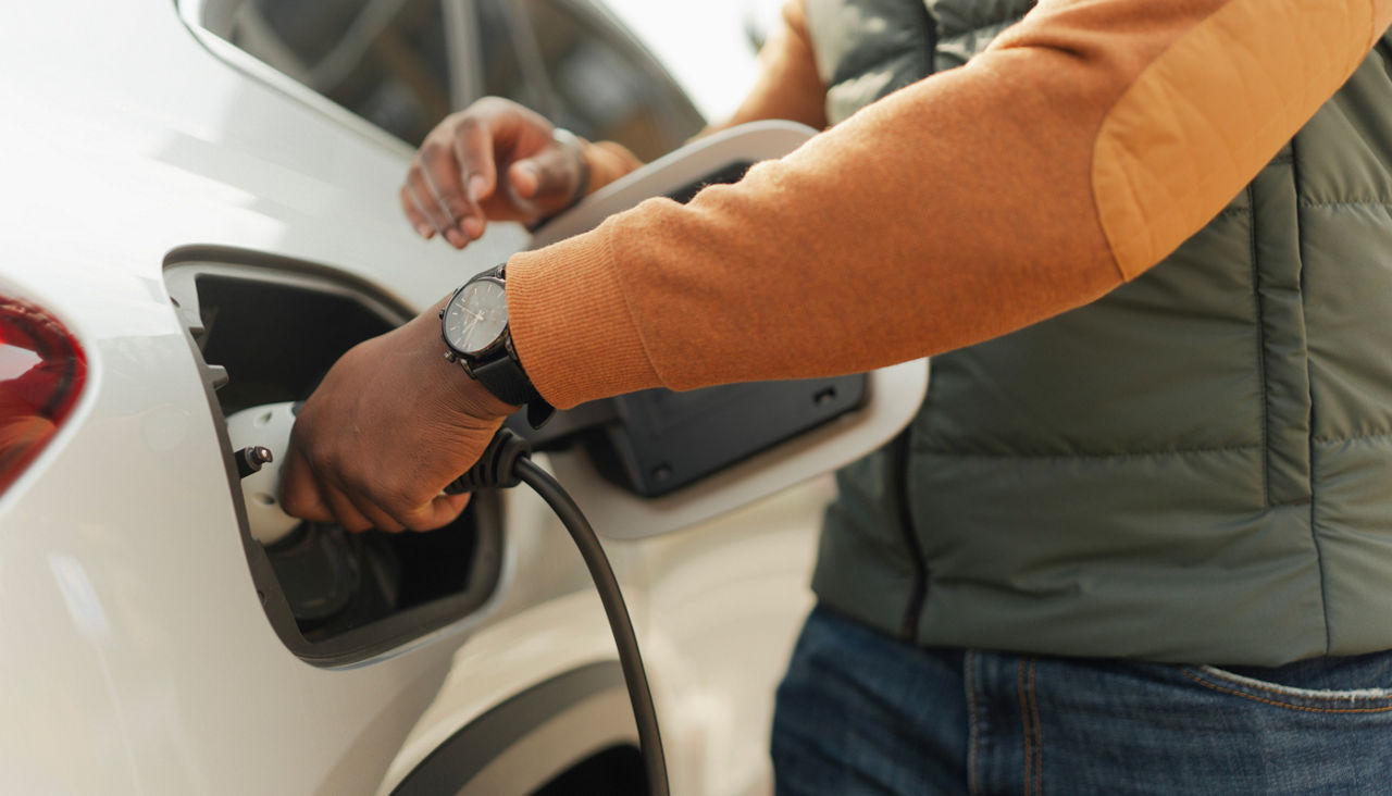 Young man charging his electric car, close-up