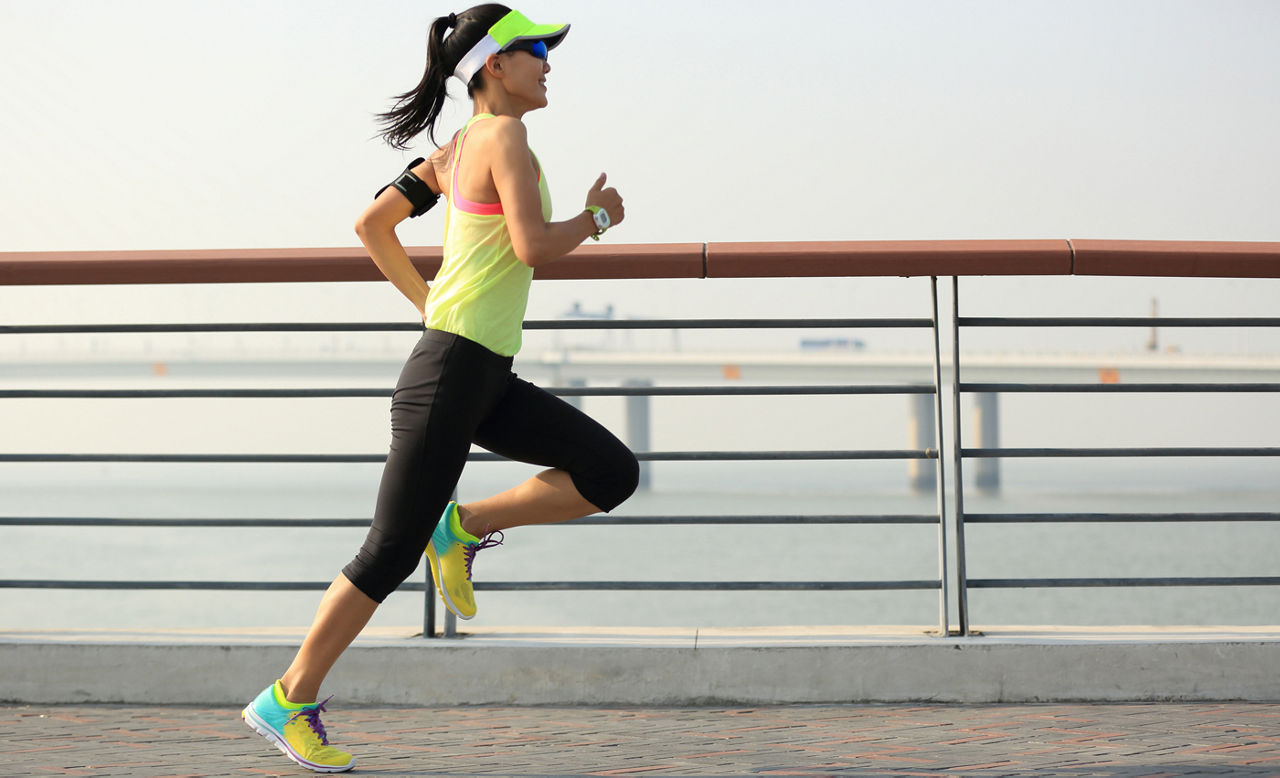 young fitness woman runner running on seaside bridge