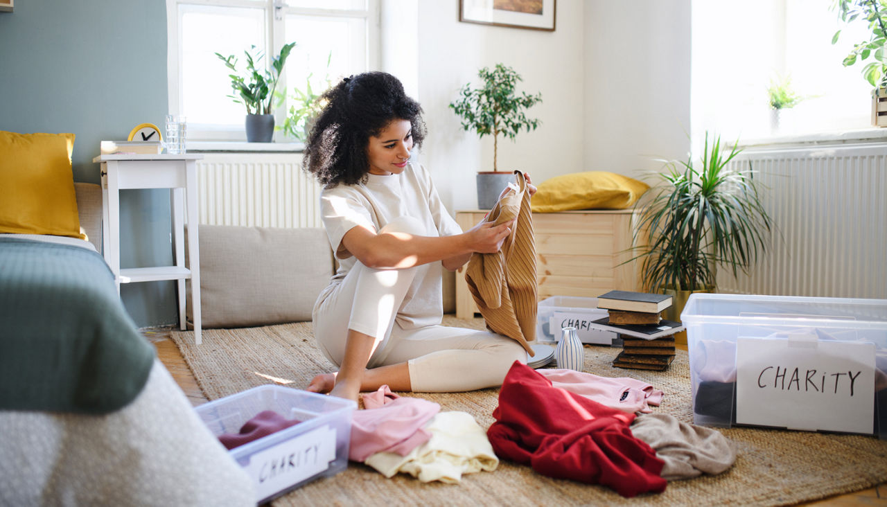 Young woman sorting wardrobe indoors at home, charity donation concept.