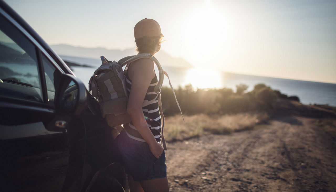 Woman relaxing on her car at the road trip