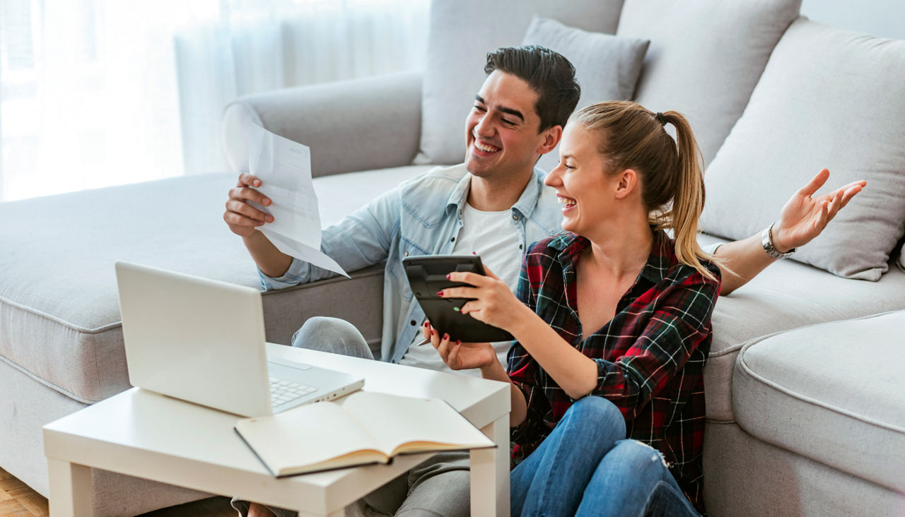 Young couple reviewing finances on laptop in the living room