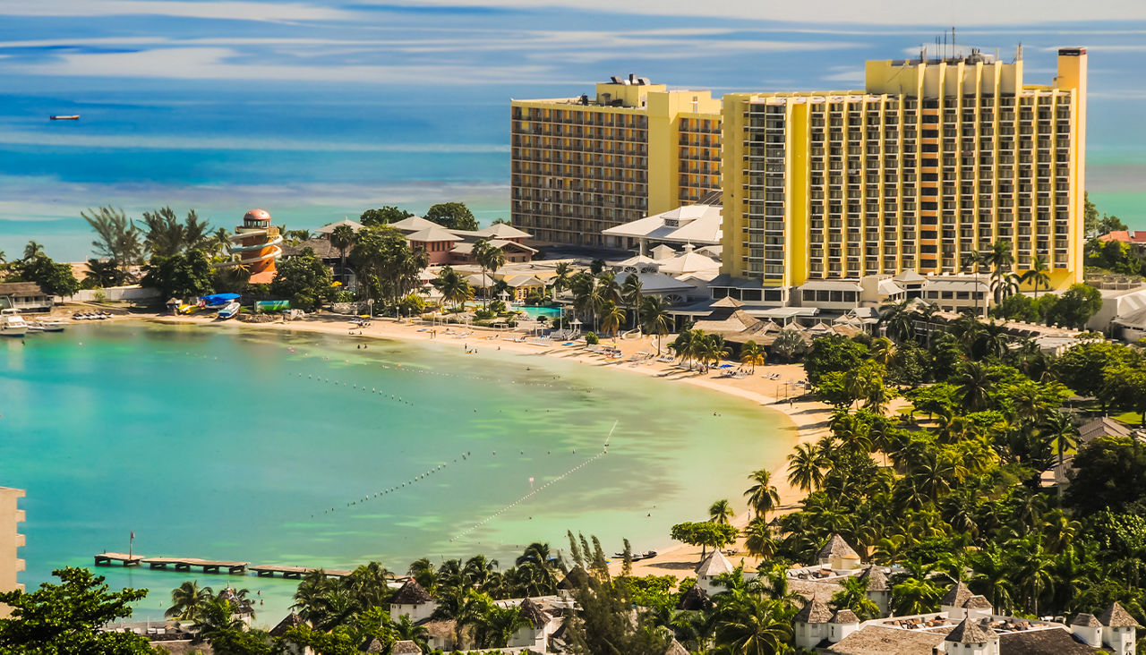 A bright yellow hotel towers over a beach.