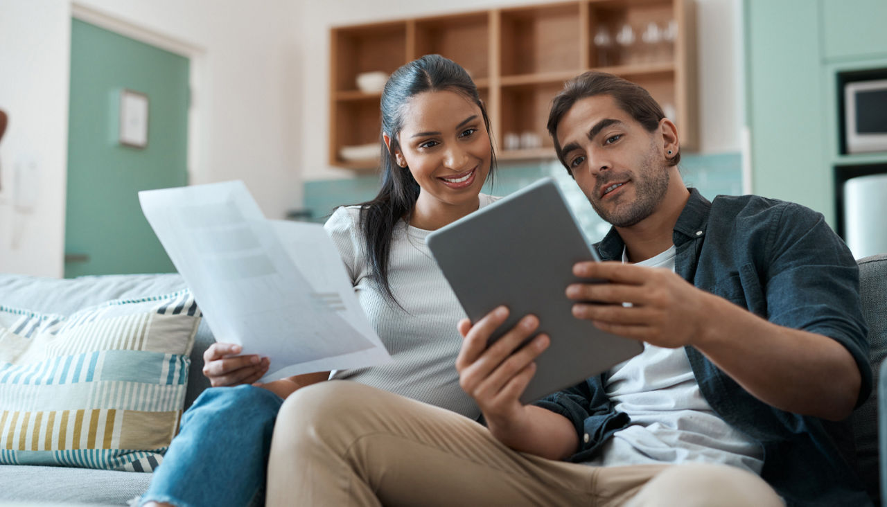 Young couple doing paperwork using a digital tablet