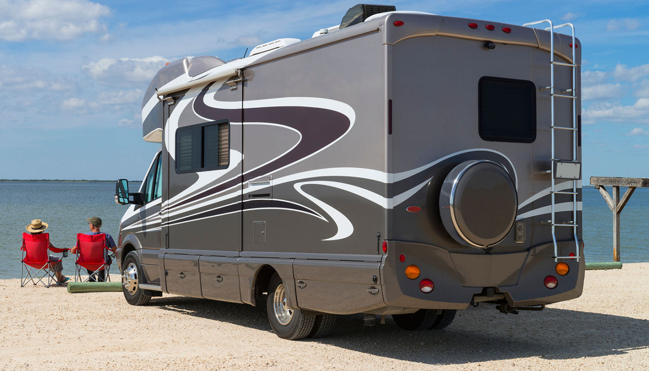 Senior ouple sitting near water with motorhome in camping