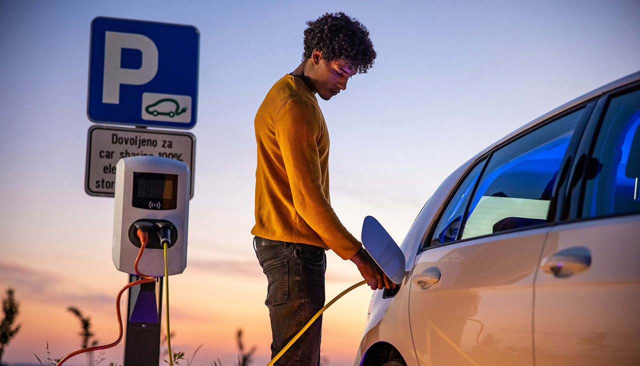 Young man charging his electric vehicle at a charging station