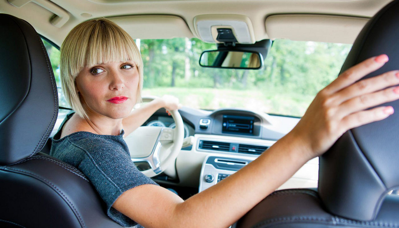 Woman in driver's seat of car looking over her shoulder to see what is behind her