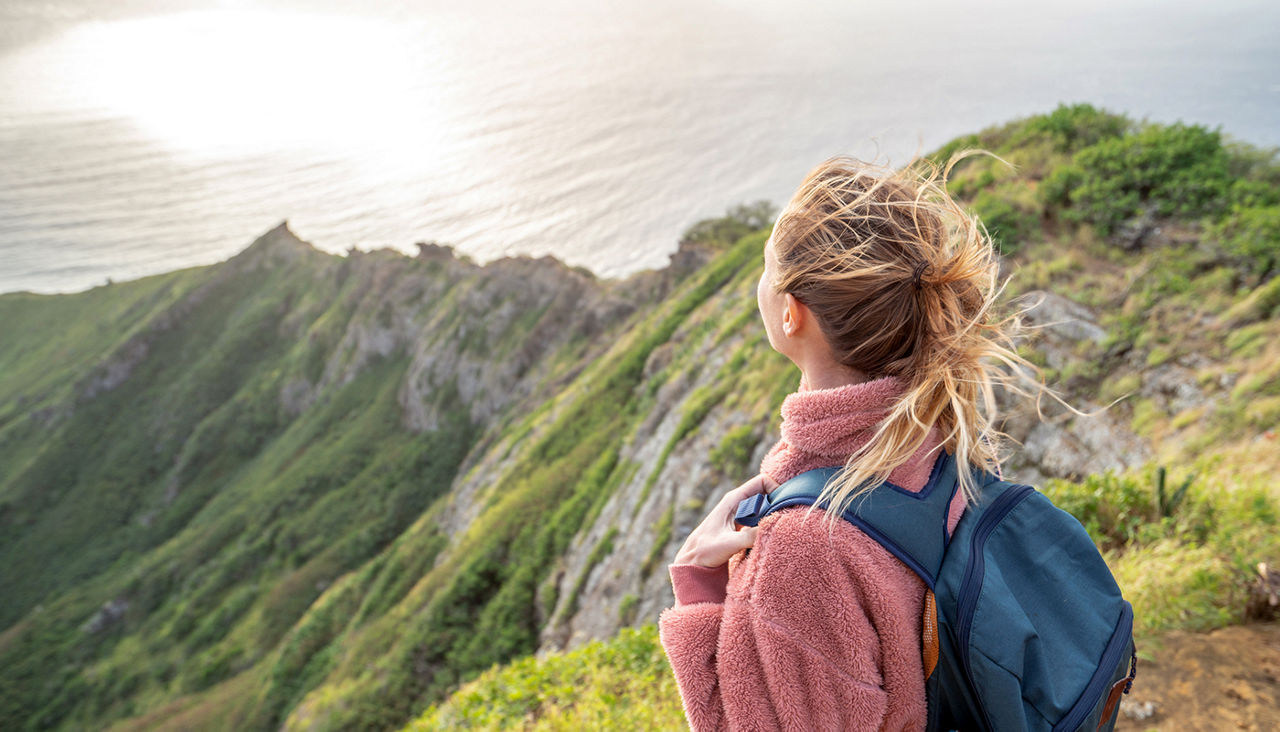 Young woman on mountain top overlooking the ocean, Oahu, Hawaii, USA