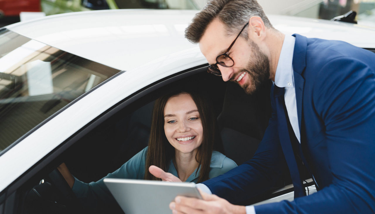 Man showing car information on a tablet to female customer