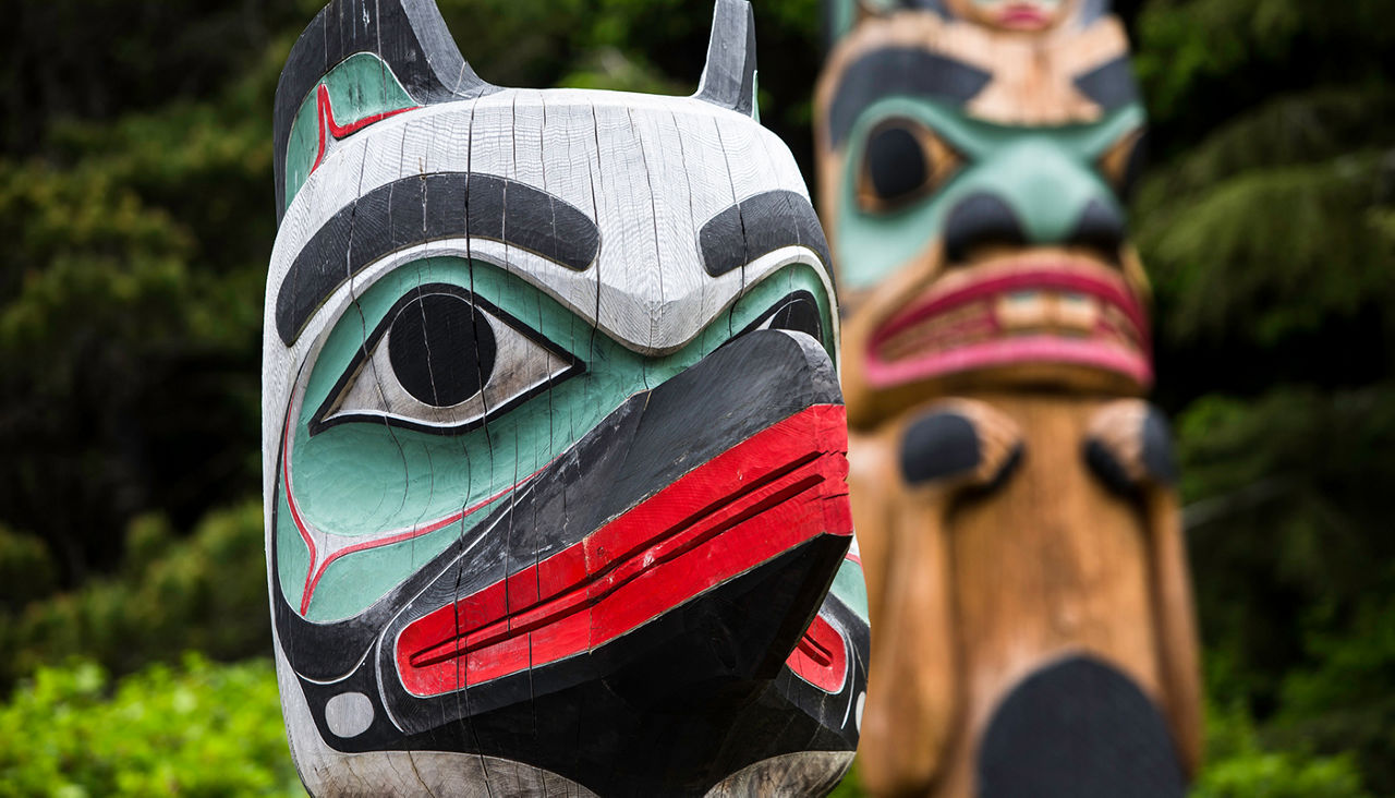 Totem Guard at Saxman Village with Beaver pole in background