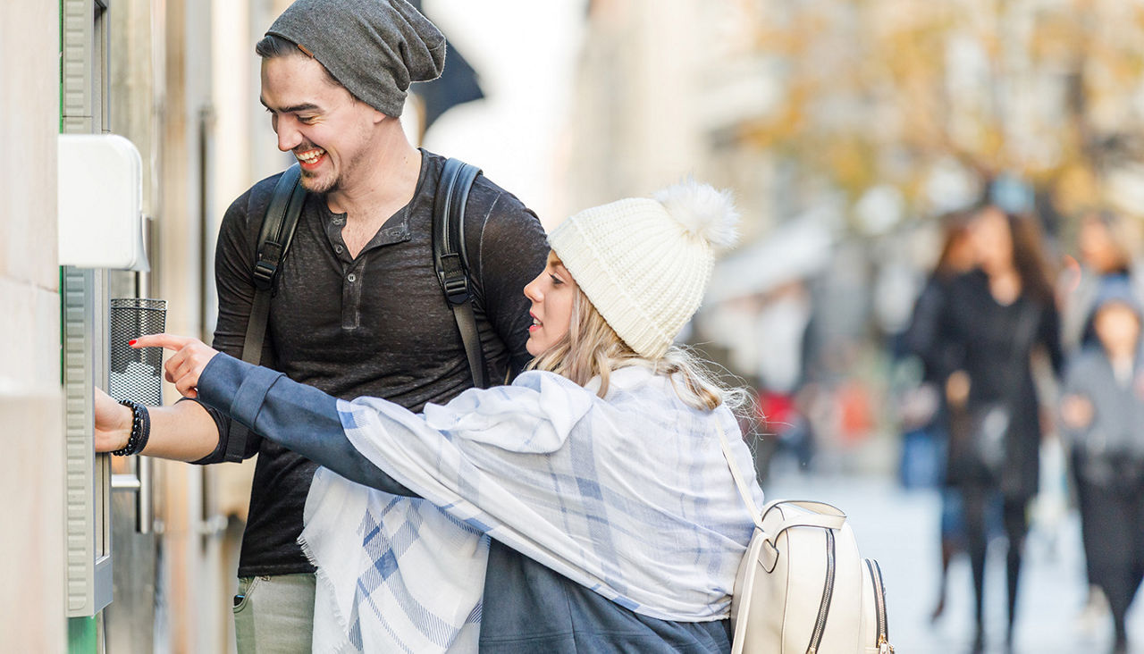 A man and woman use an ATM.