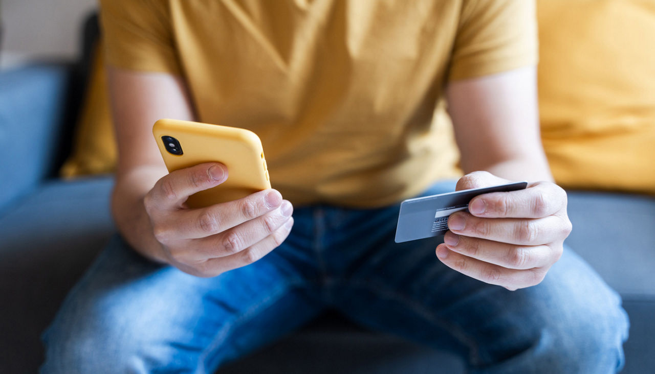 Man using smartphone to make a purchase with credit card in hand