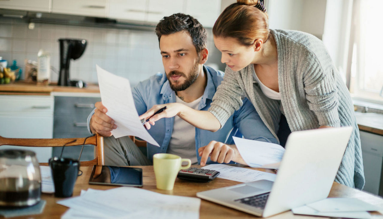Young couple going over bills and payments together in the kitchen