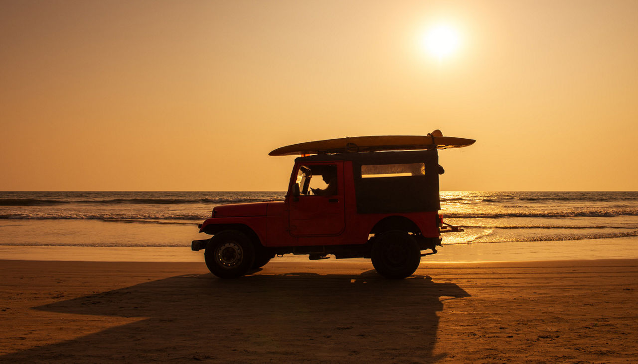 Jeep with surf boards on beach at sunset