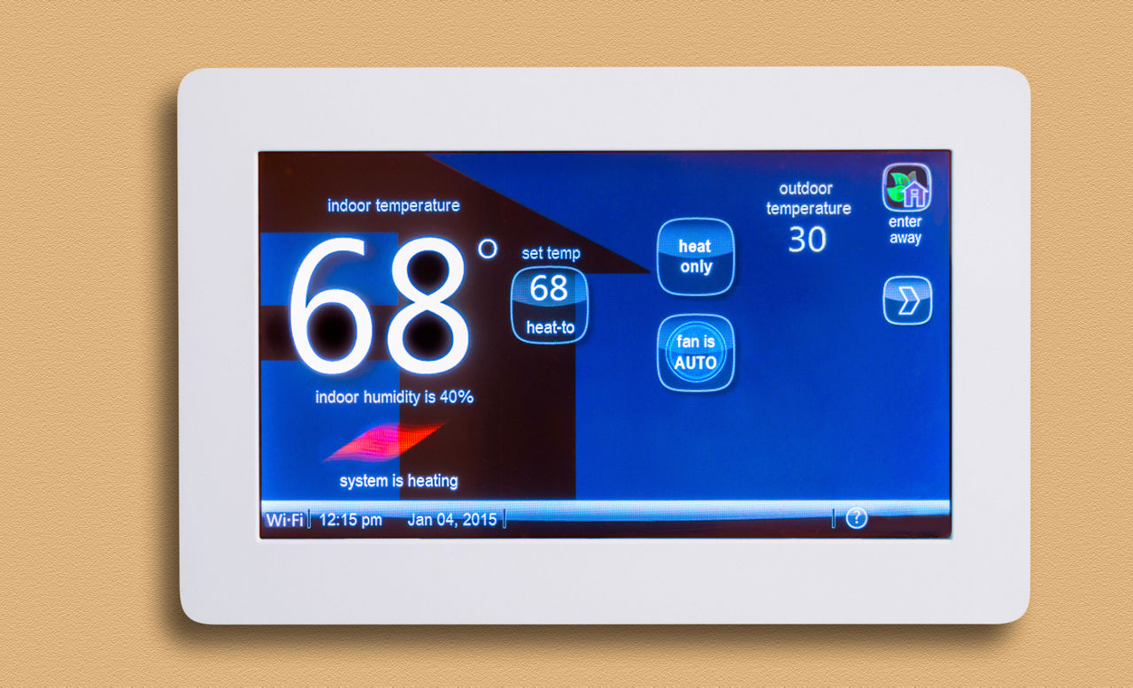Electronic smart thermostat on wall reading 68 degrees