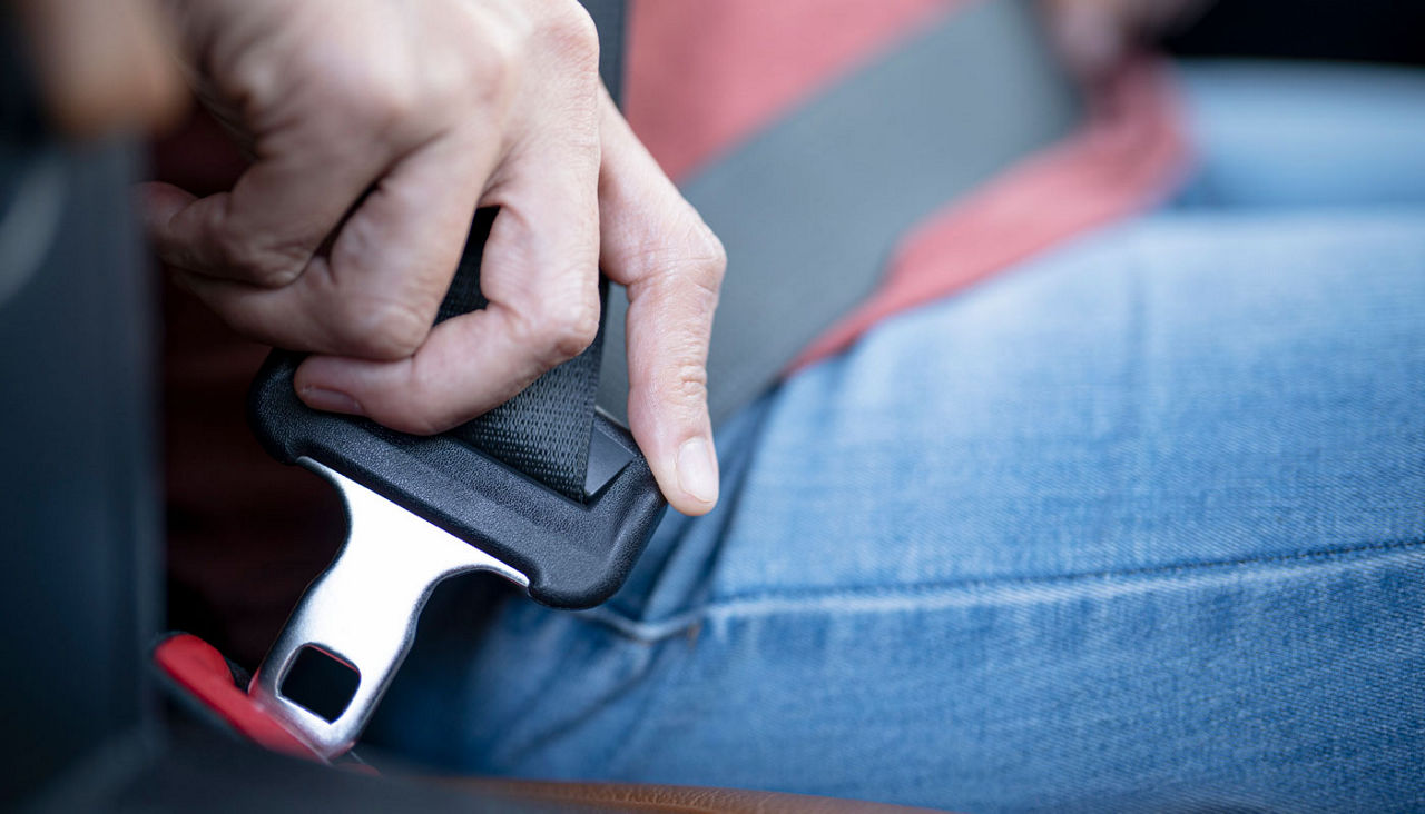 A close-up view of a person clicking their seat belt into the latch