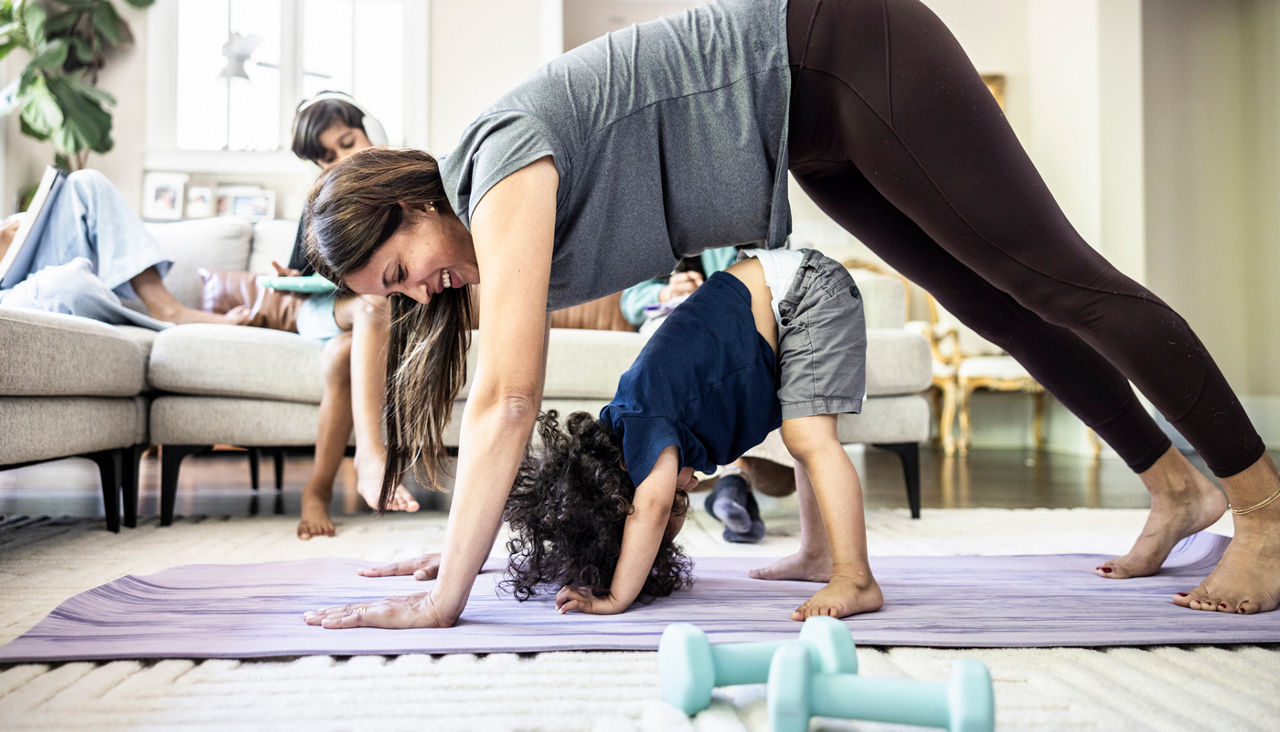 Mother exercising at home with her toddler son mimicking her position