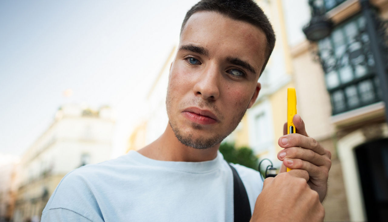 Blind young man using smartphone with artificial intelligence adapted for accessibility