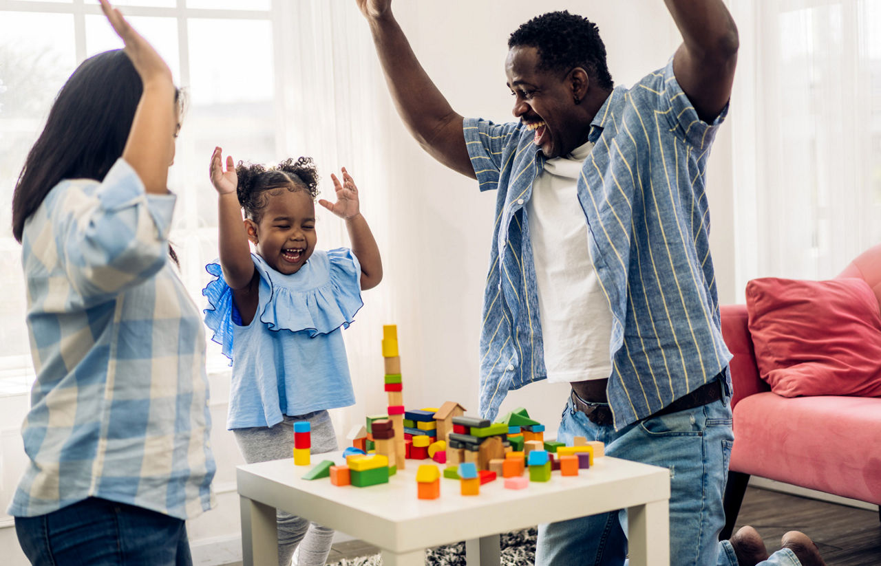 Mother and father playing with their young daughter with building blocks