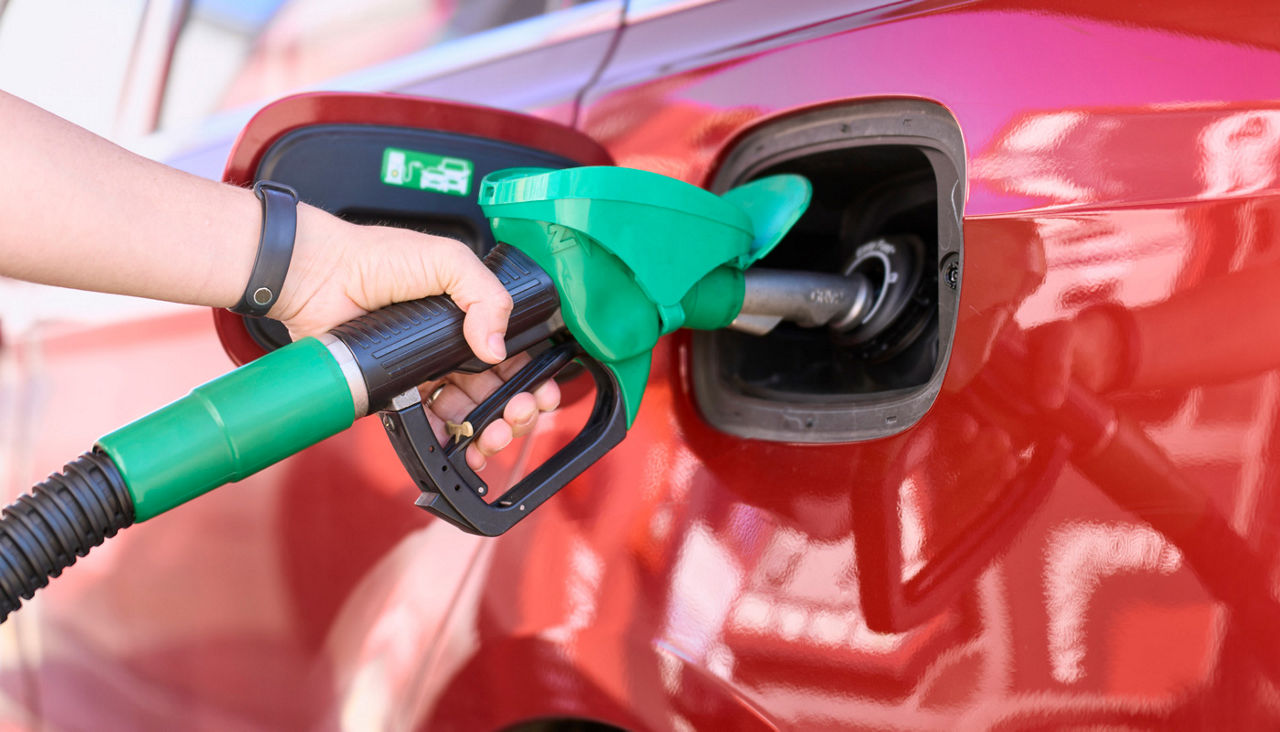 Close-up of a woman standing at a gas station filling her car with gasoline