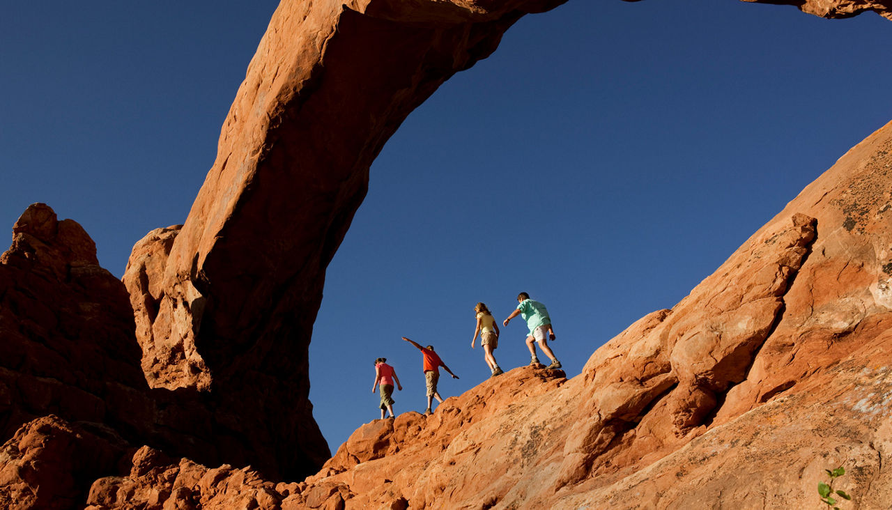 Family of Four Walking On Rocks In Arches National Park