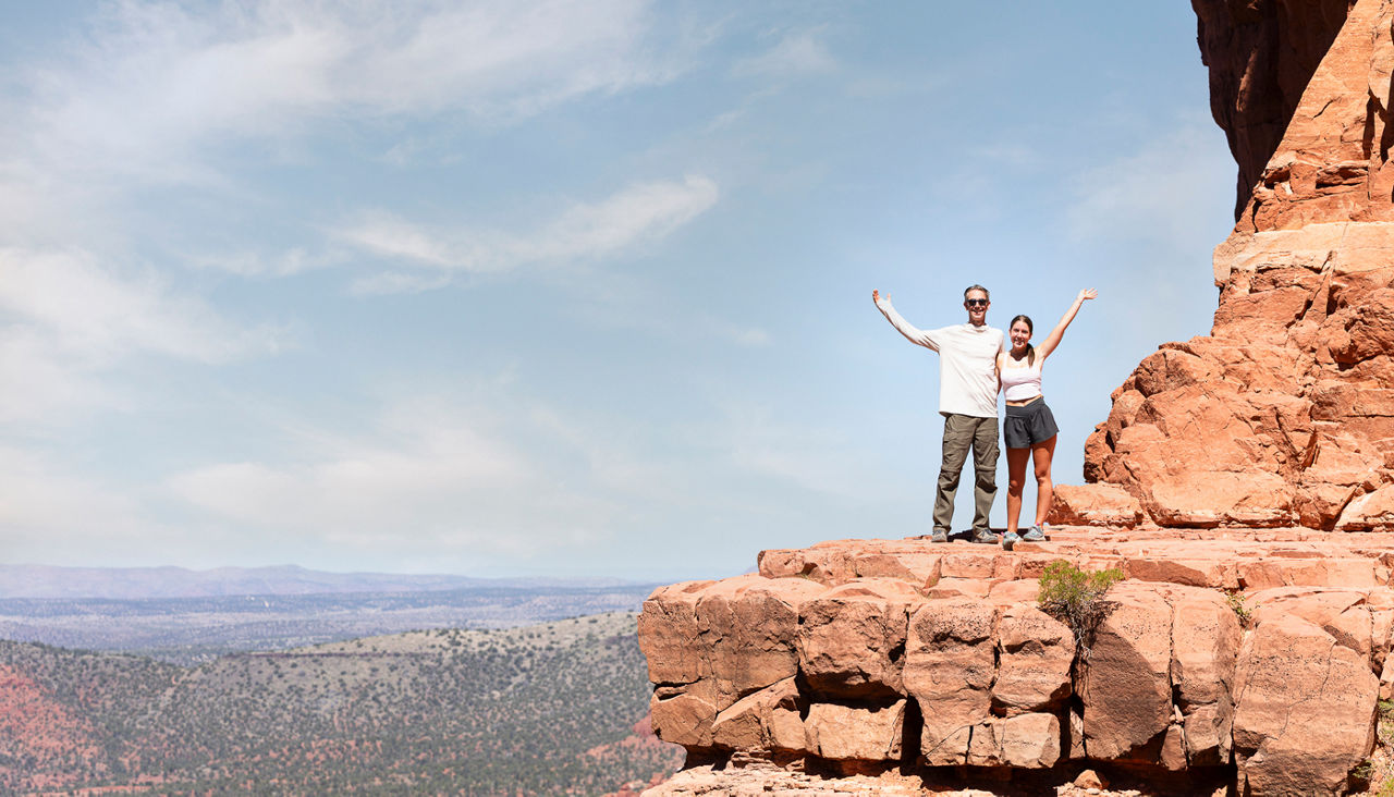 Two pose on side of cliff in Sedona