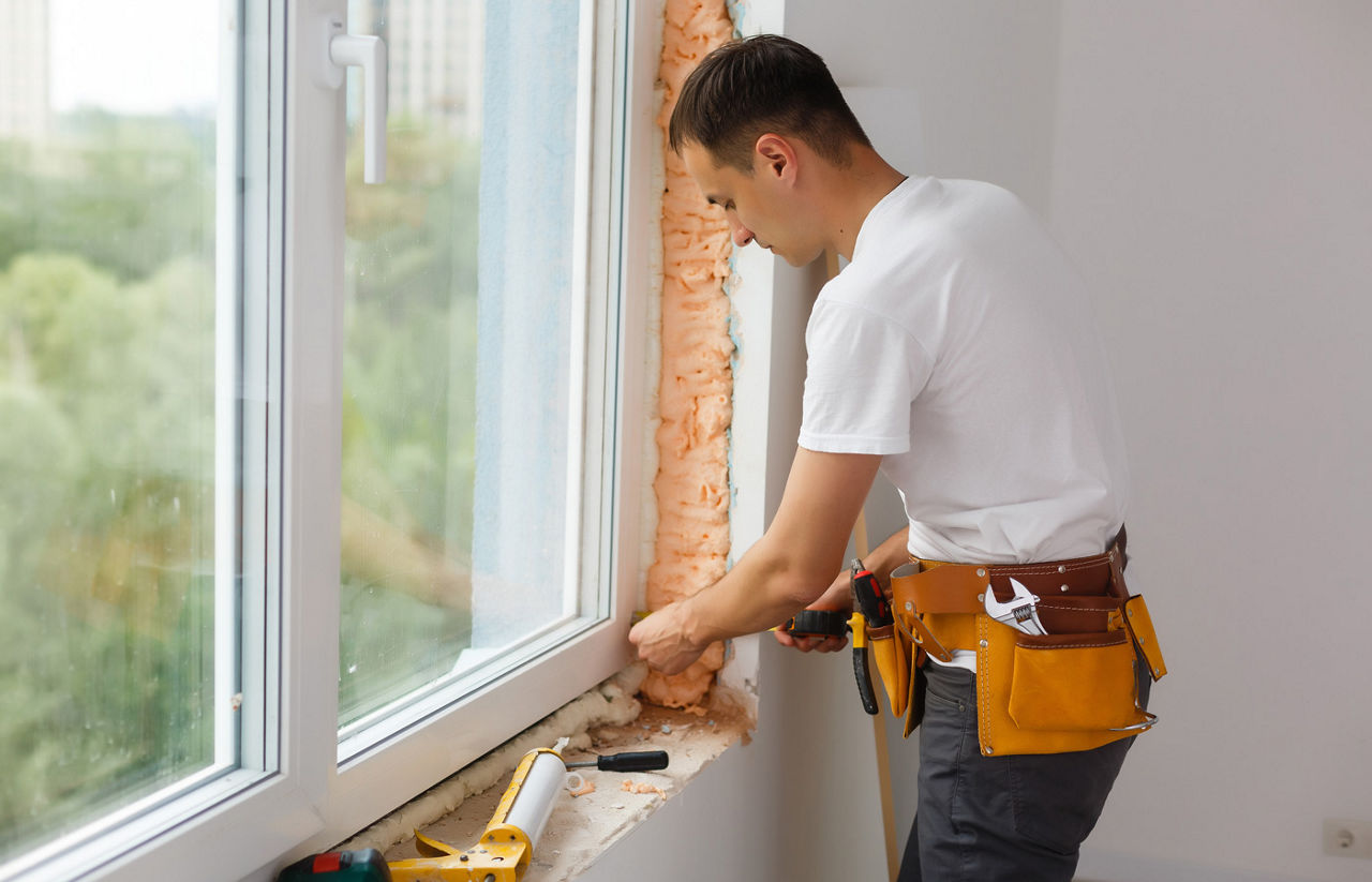 Man installing window from inside of room