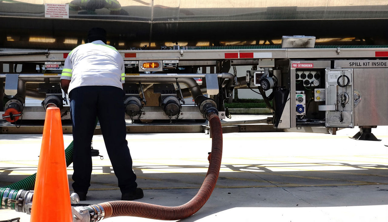 Fuel delivery driver checks the valves as gas is delivered from his tanker to the underground storage tanks at a local gas station.