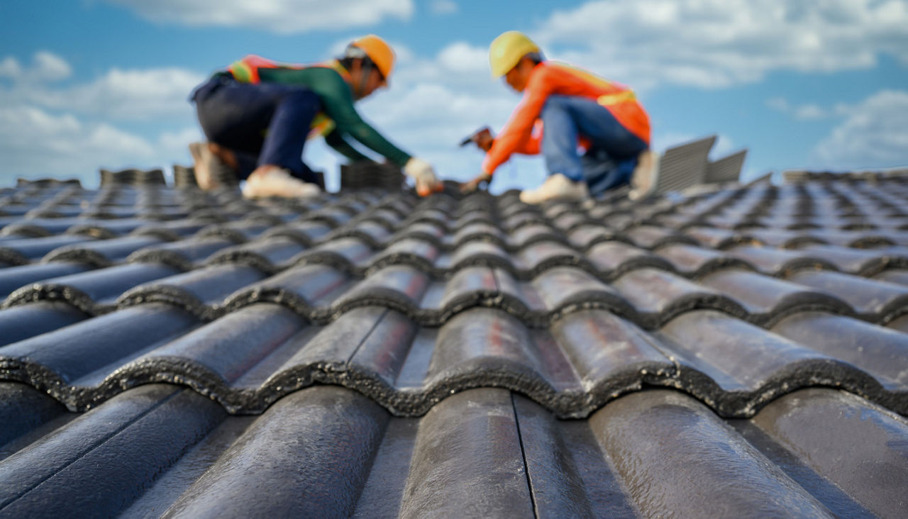 Two workers installing ceramic tile roof