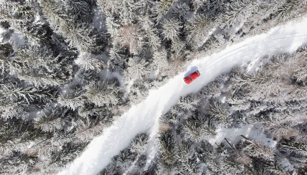 car on dangerous snowy road through forest